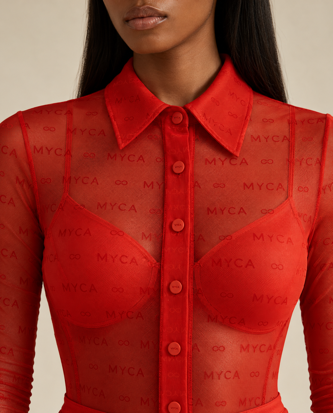 Close up macro view of the MYCA Carnelian sheer mesh long sleeve bodysuit highlighting the structured collar, tonal button front placket and signature monogram and infinity print fabric quality 