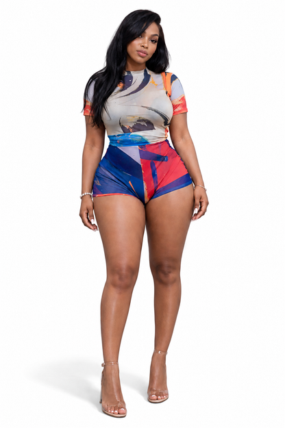 Full-length view of a model wearing The MYCA Canvas Body Series abstract print bodycon set, featuring a short-sleeve mesh bodysuit and matching mini shorts with a blue, orange, and red paint stroke pattern against a solid white background.